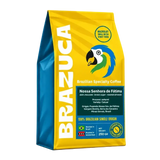 Een zak van 250 g Brazuca Brazilian Specialty Coffee, met een felgele en blauwe verpakking, een papegaailogo en verticale witte merknaam.