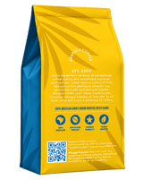 A standing bag of Brazuca Coffee Roastery single origin coffee beans, showing the back panel with a bright yellow and blue design, text, icons, and a QR code on a white background.